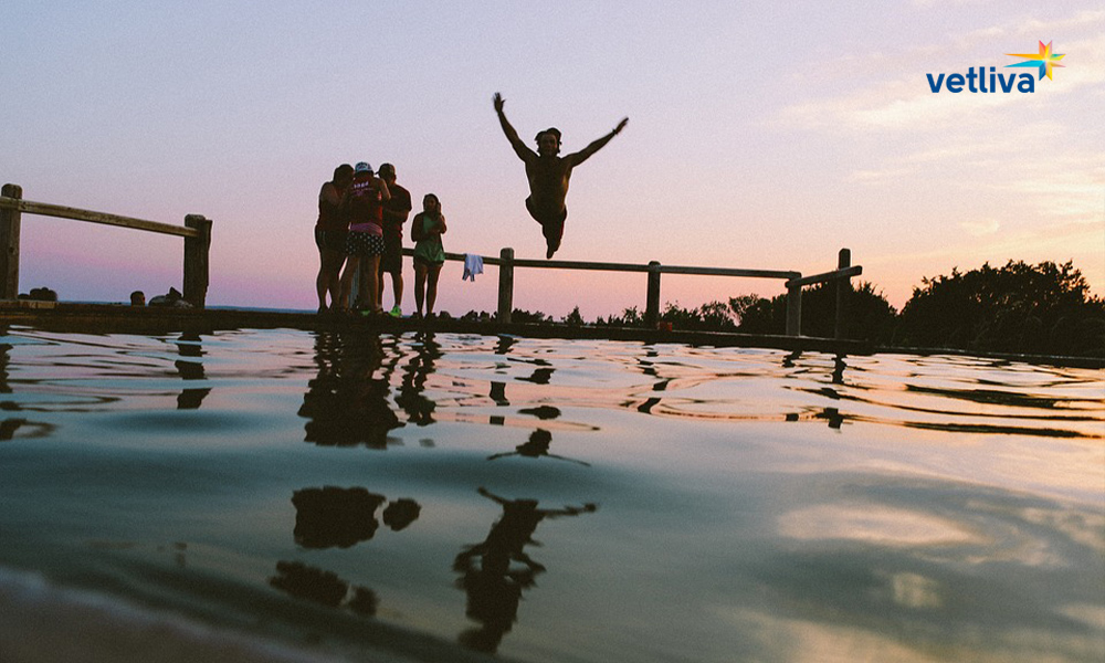 Компания друзей прыгает в воду с пирса